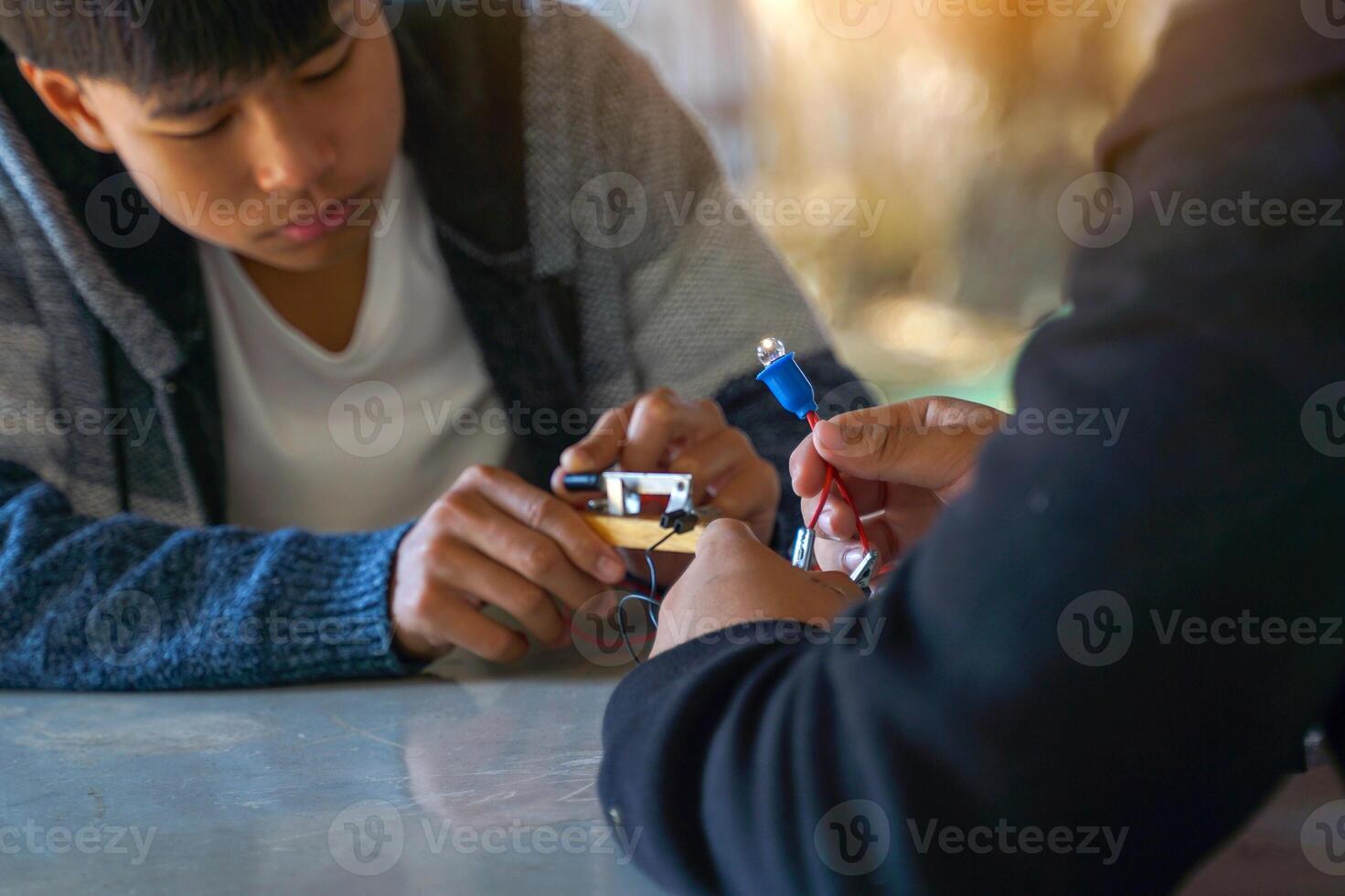 Thai student performs an outdoor science experiment on connecting a simple electrical circuit by connecting light bulbs in series and observing their brightness. photo