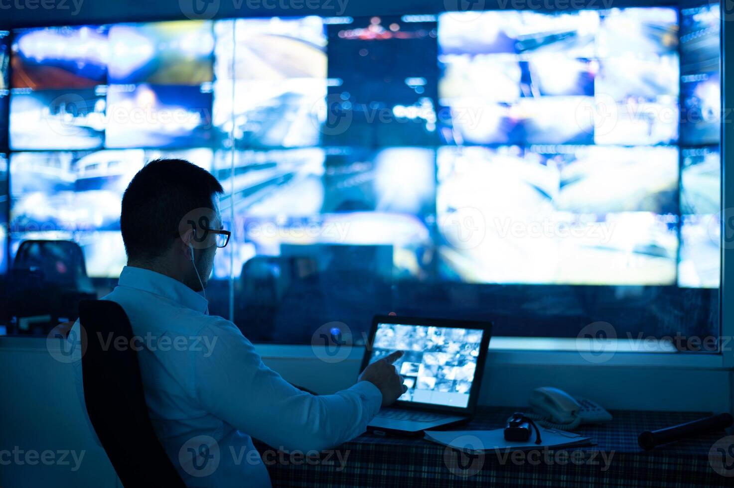A cctv officer is sitting and checking images from a cctv camera displayed on a laptop screen. photo
