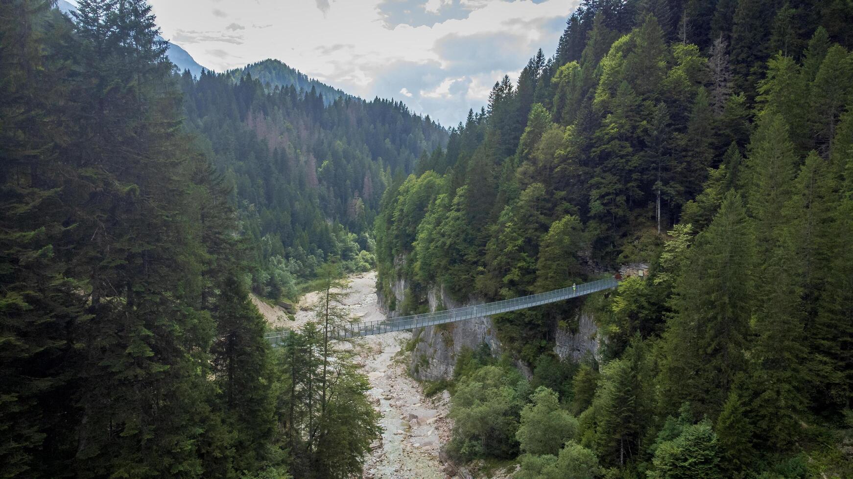 Tibetan bridge in a canyon in the middle of nature landscape. Aerial view of a suspended rope bridge in Noana Valley in Trentino photo