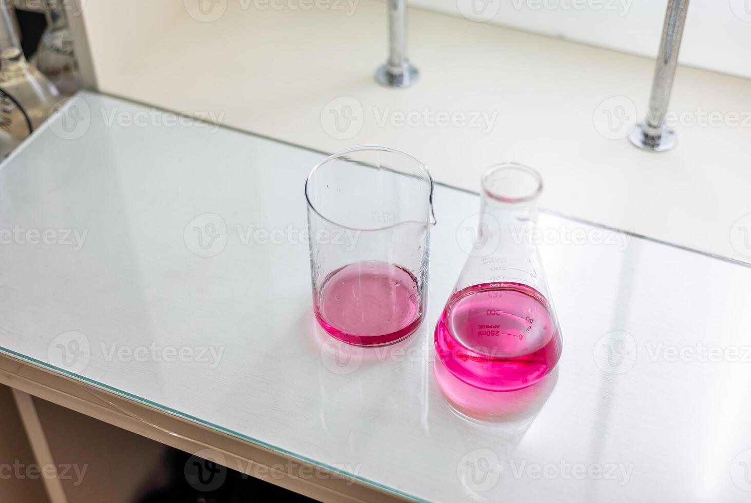 Two beakers and a glass on a counter photo