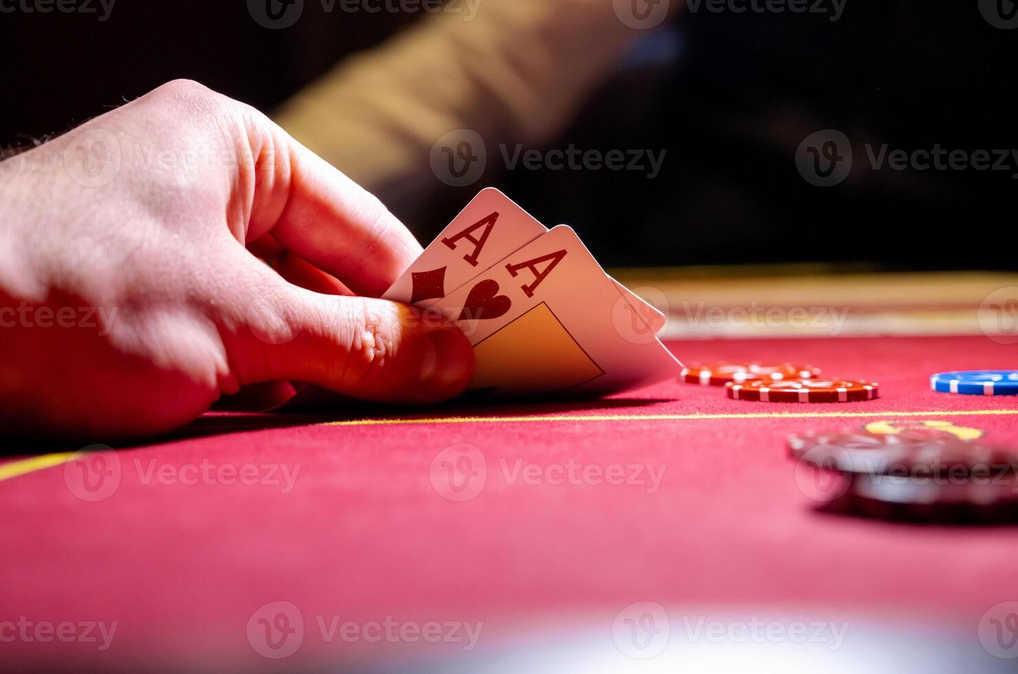 A person holding a card and playing cards on a red table photo