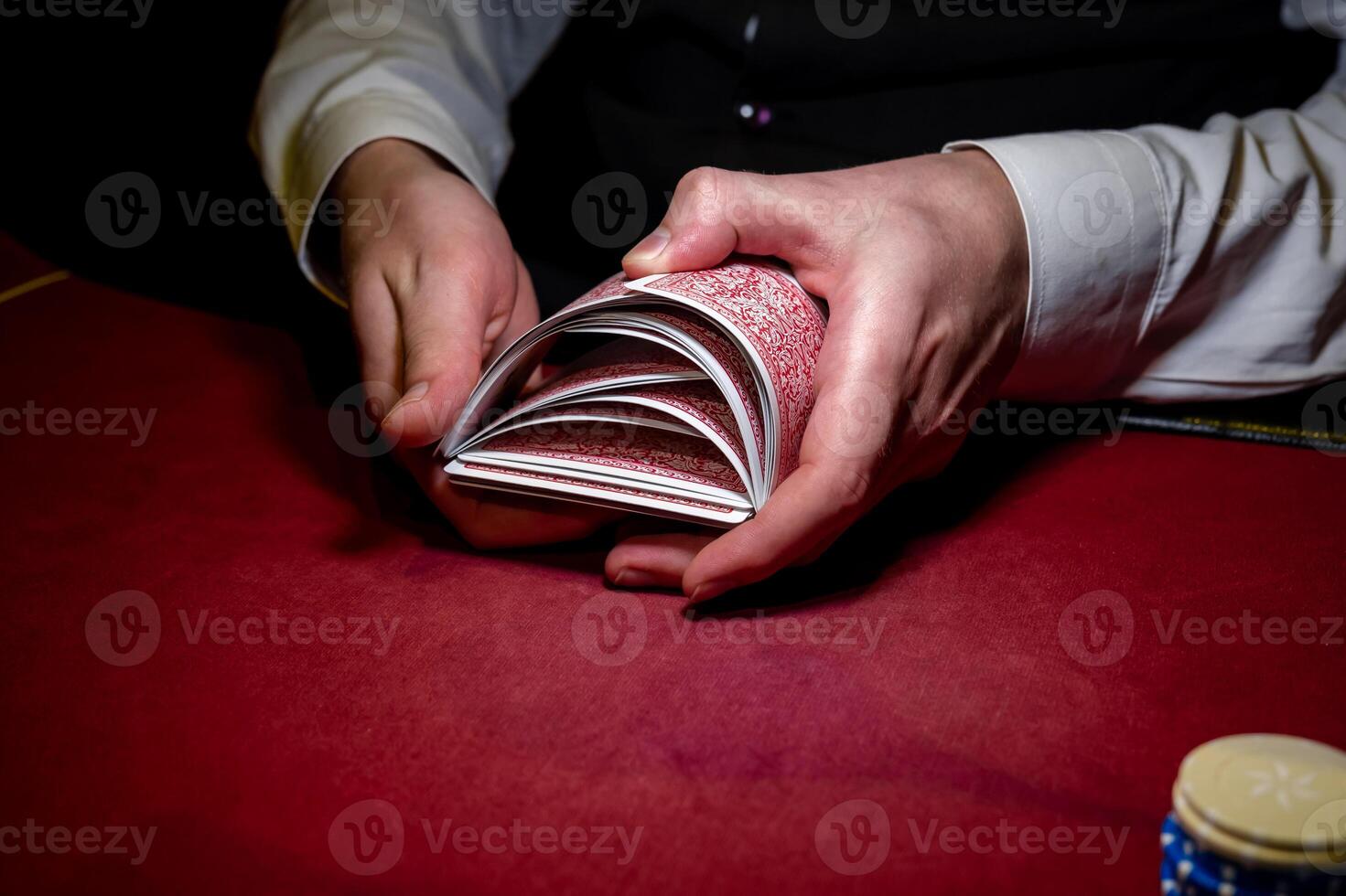 A man holding a stack of cards on a red table photo