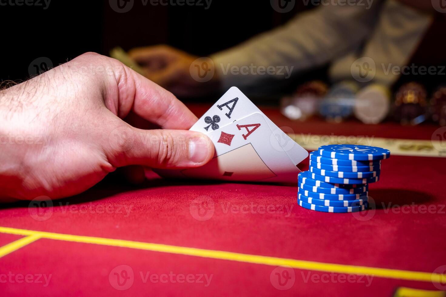 A person holding a card and playing cards on a casino table photo