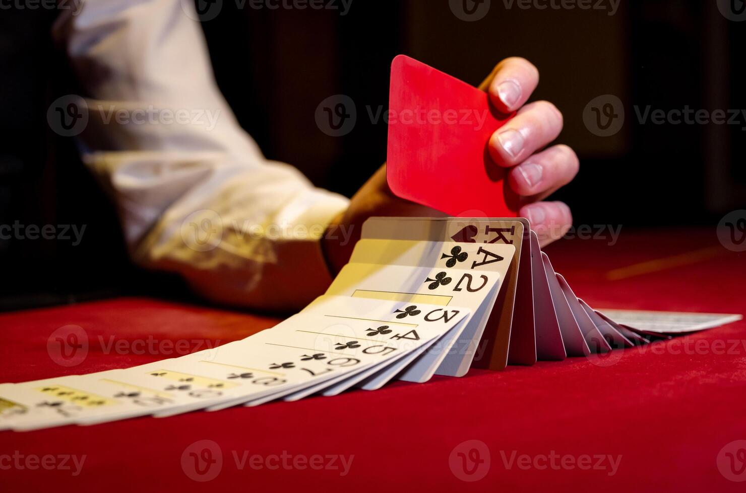 A person holding a red card in front of a stack of cards photo