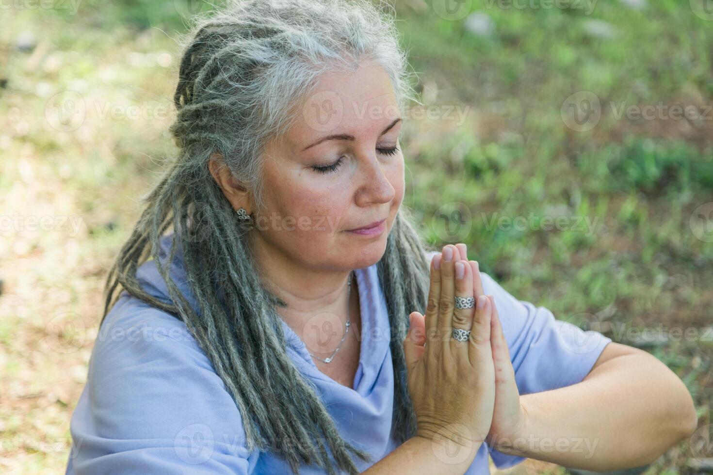Mindful senior woman portrait with dreadlocks meditating on nature close up - wellness and yoga practice photo