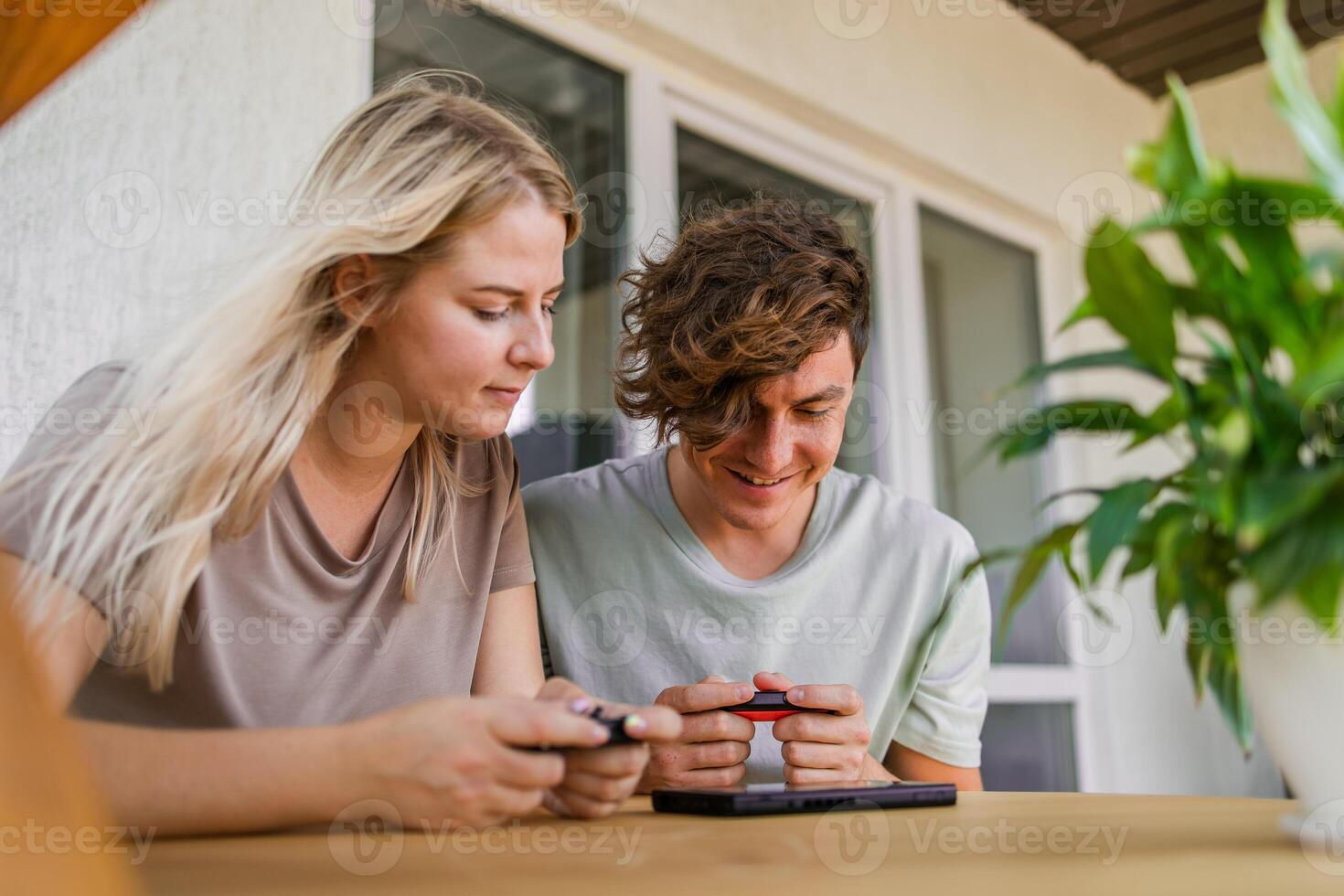 Man and woman watching a game console in a terrace in summer. Technology and game addiction concept photo