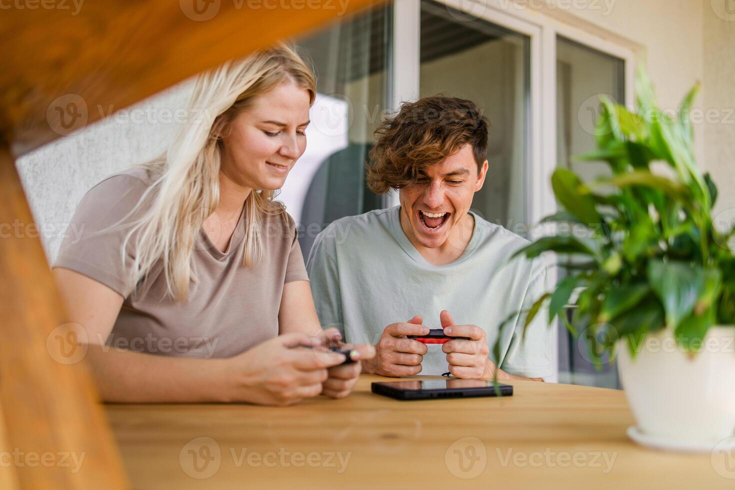 Joyful man and woman playing games on terrace. Technology and game console concept photo