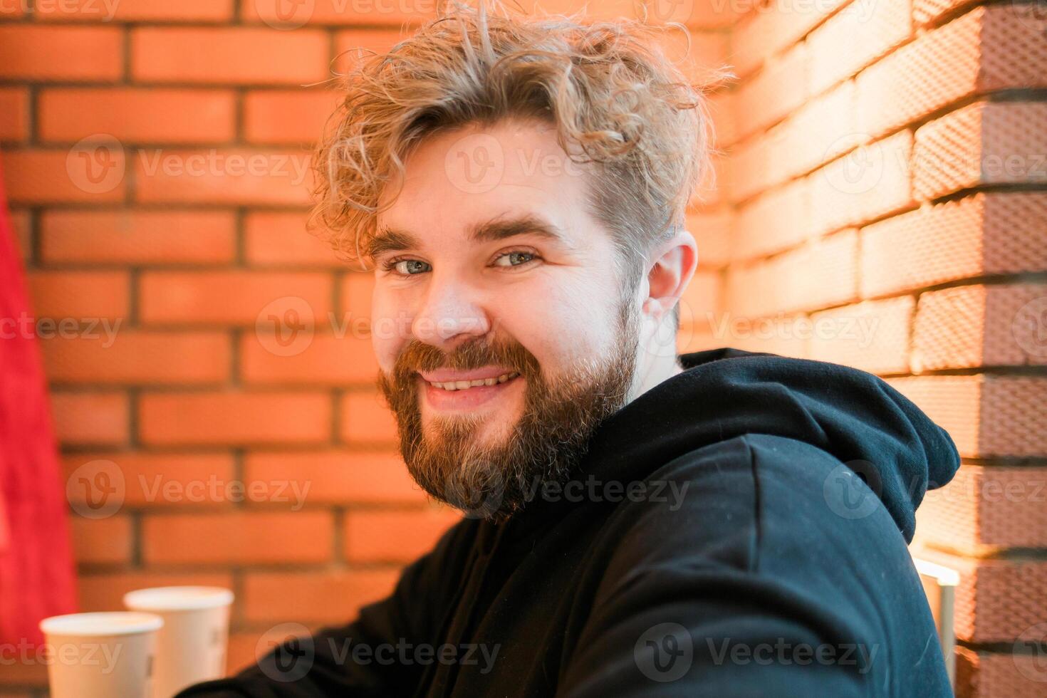 Bearded happy man smiling portrait while sitting in cafe or coffee shop photo