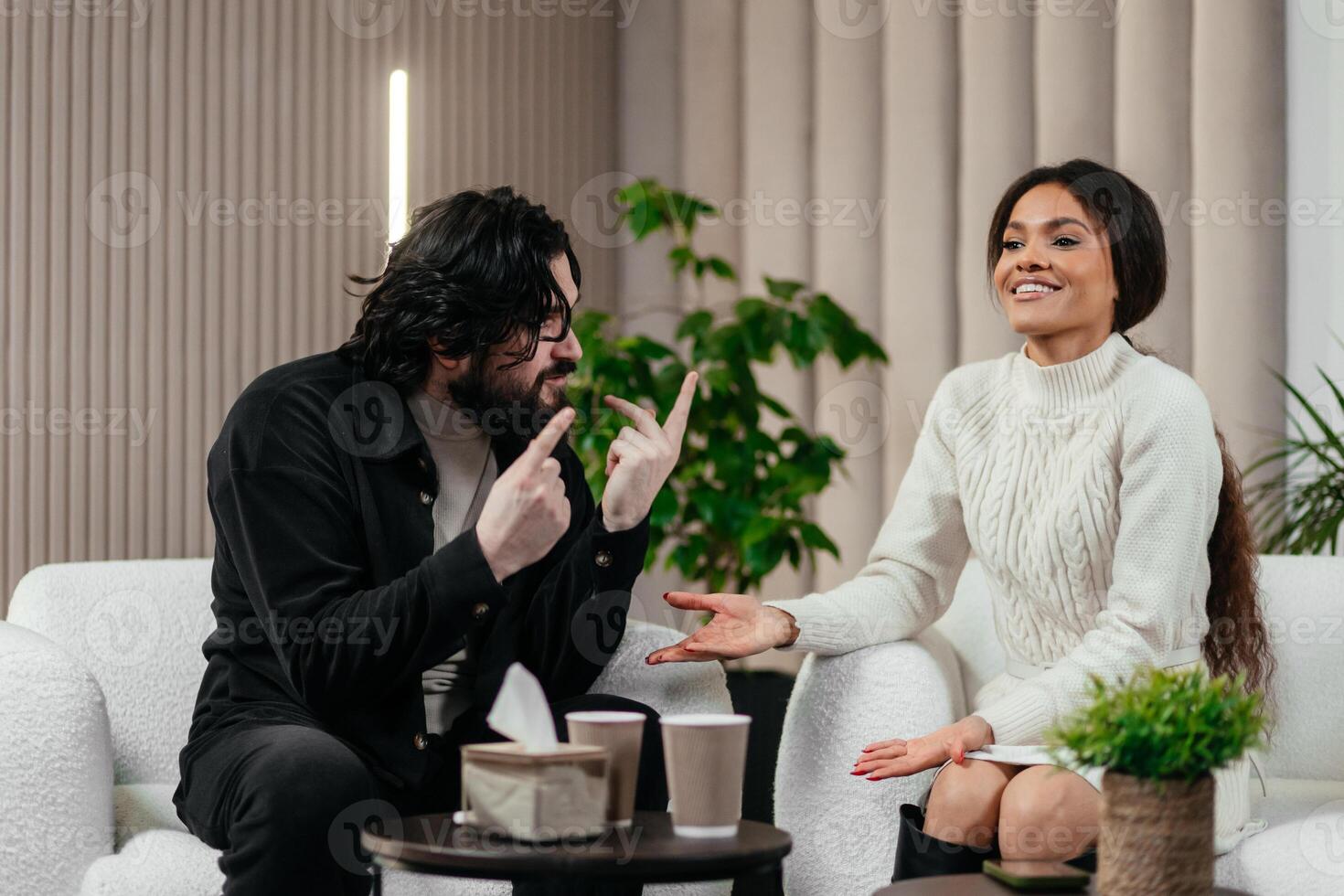 Multiracial couple to therapist in an indoor living room, expressing emotions and discussing mental health while sitting on a comfortable couch photo