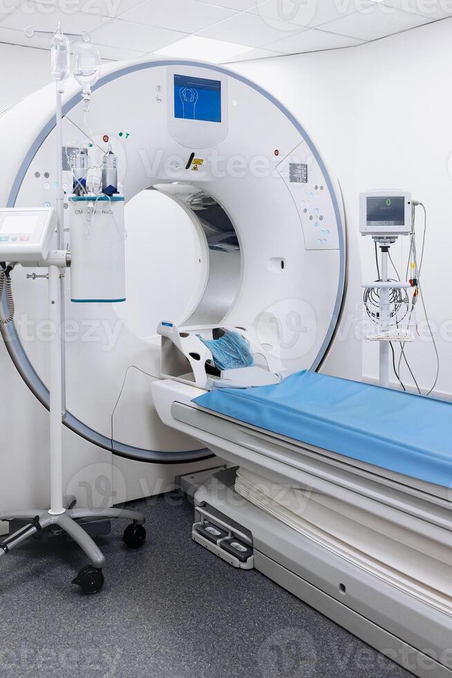 A high-angle shot of a CT scan machine room, showing the advanced medical imaging equipment and the clean, organized environment of the room. Vertical shot, advertising photo