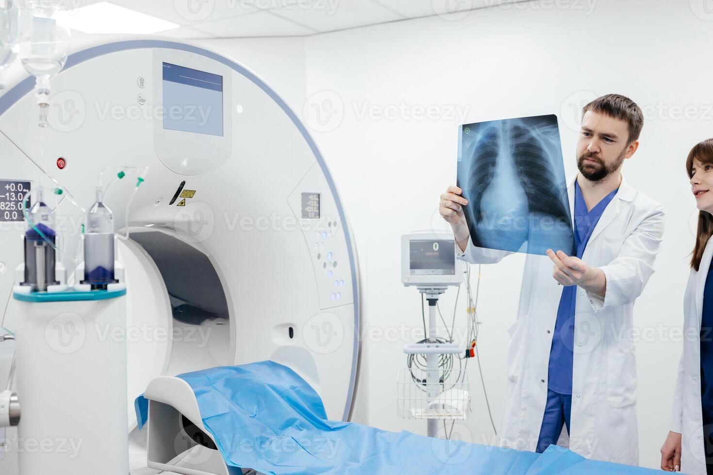 Team of doctors watching x-ray image in a hospital. Lung disease. Doctor examining chest x-ray against white MRI room background. MRI or CT scan in a modern diagnostic center. Check-up, radiology photo