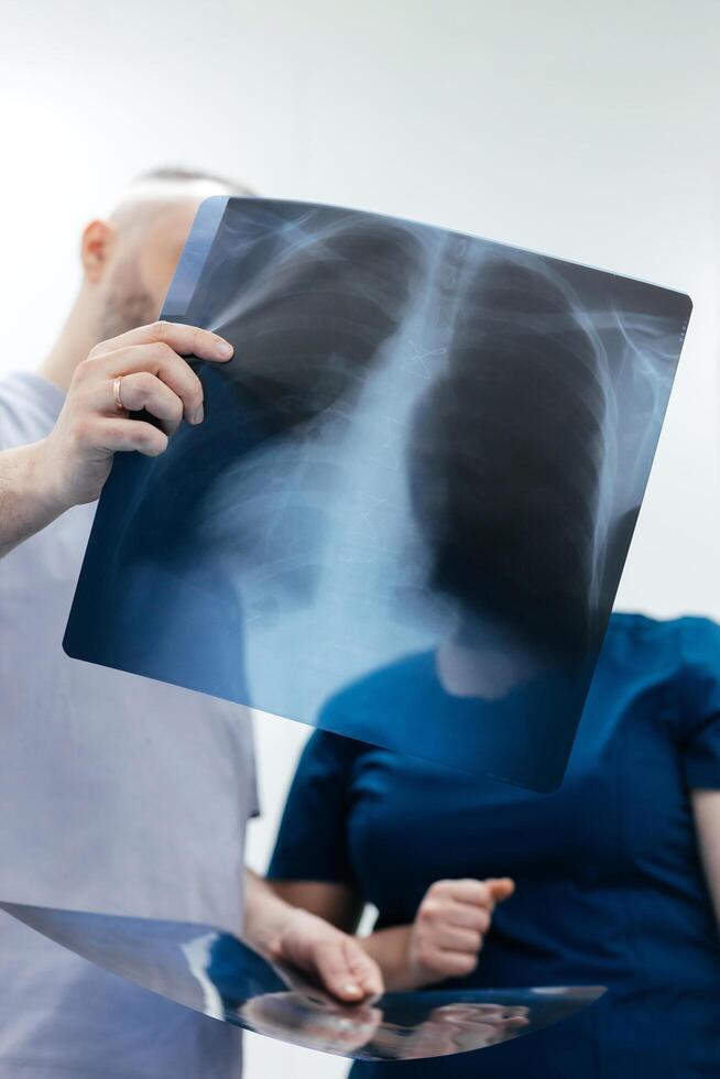 Doctor and specialist in an MRI or CT room analyze images, discussing the examination results. The concept of effective teamwork for accurate diagnostics. Vertical shot, advertising photo