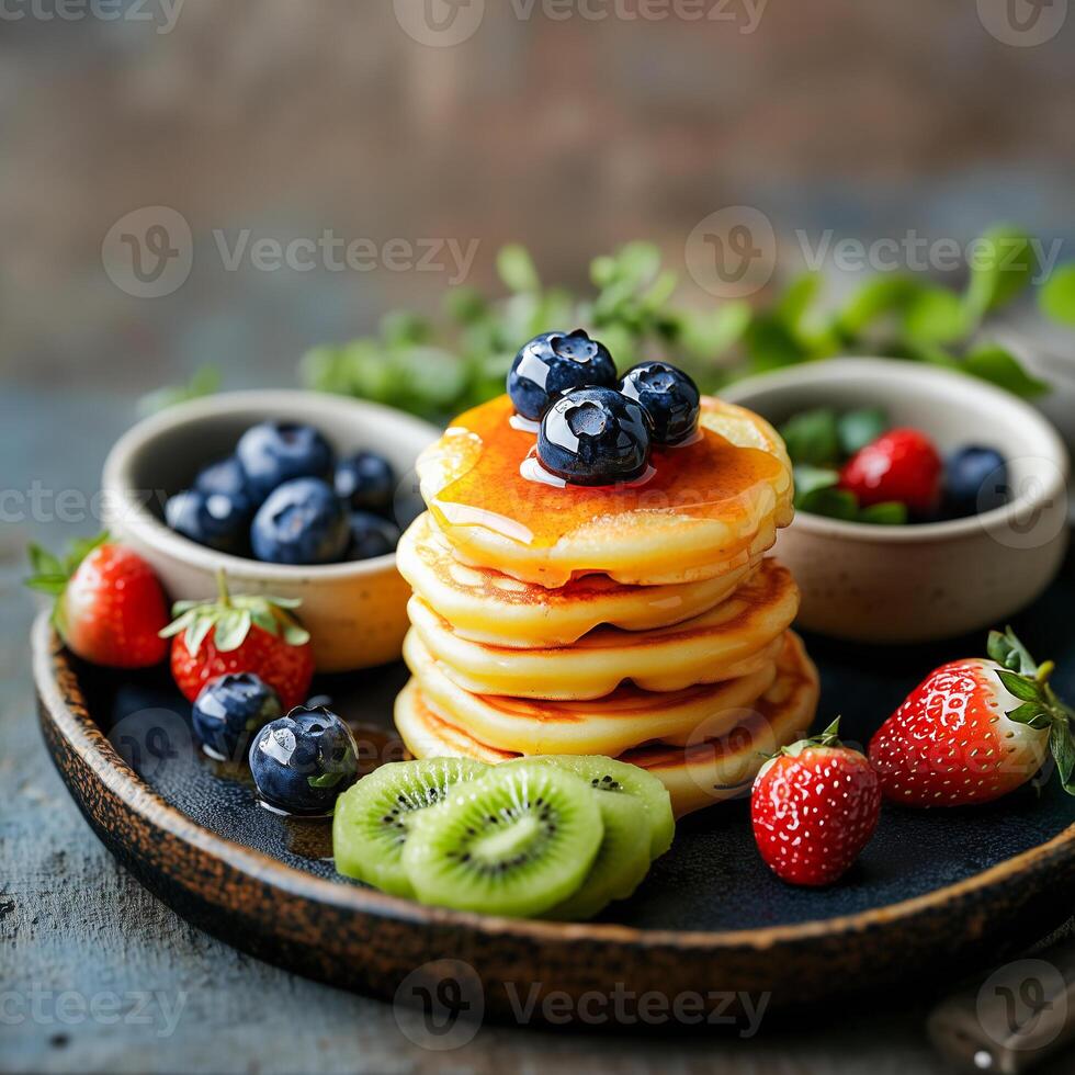 Delicious stack of mini pancakes topped with fresh berries and kiwi, served on a rustic plate. photo