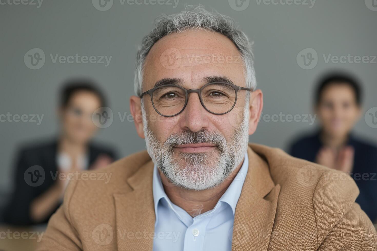 Close up mature man in business setting with two colleagues in background. photo
