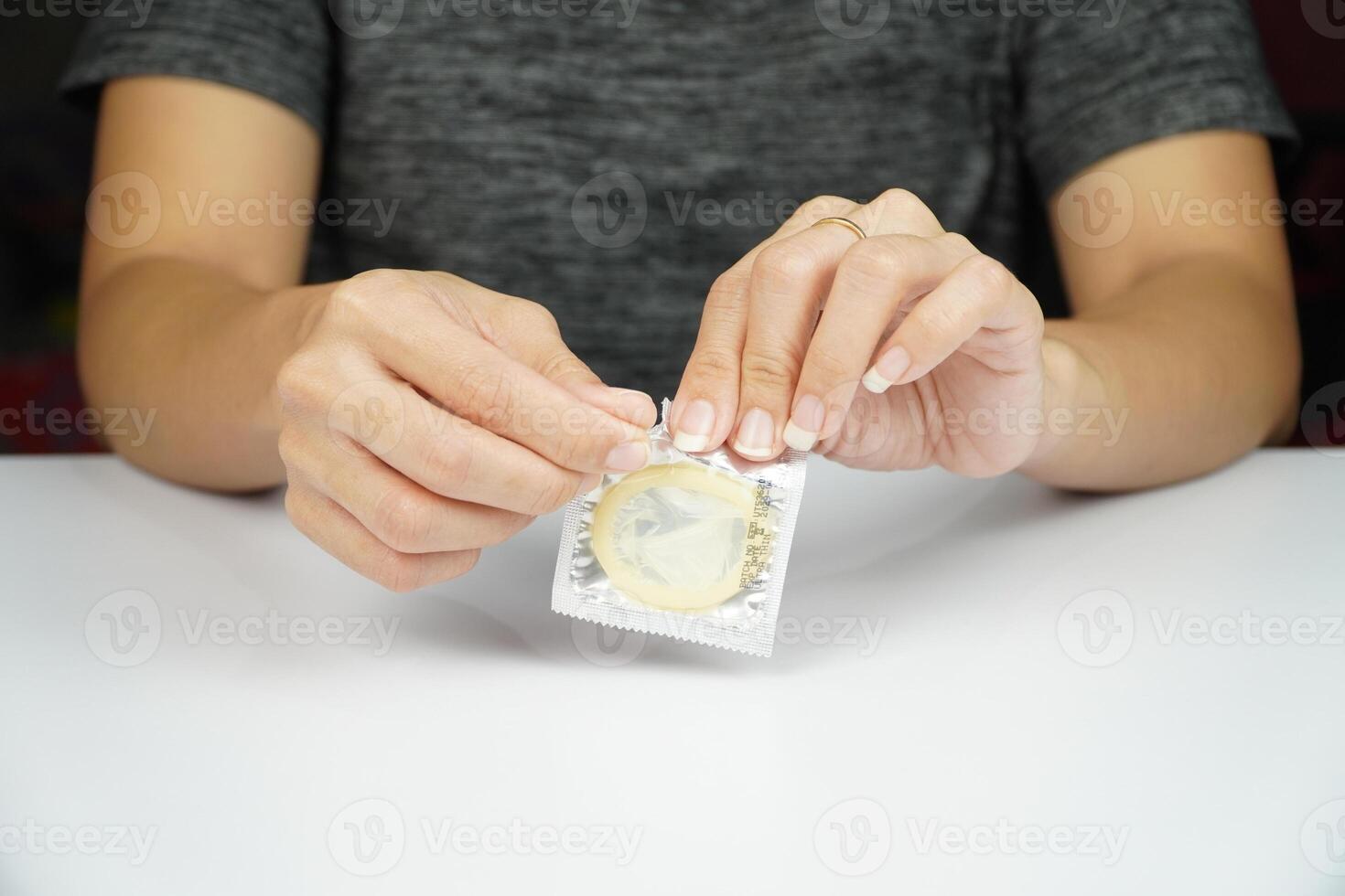 A woman holding a condom packet on a table photo