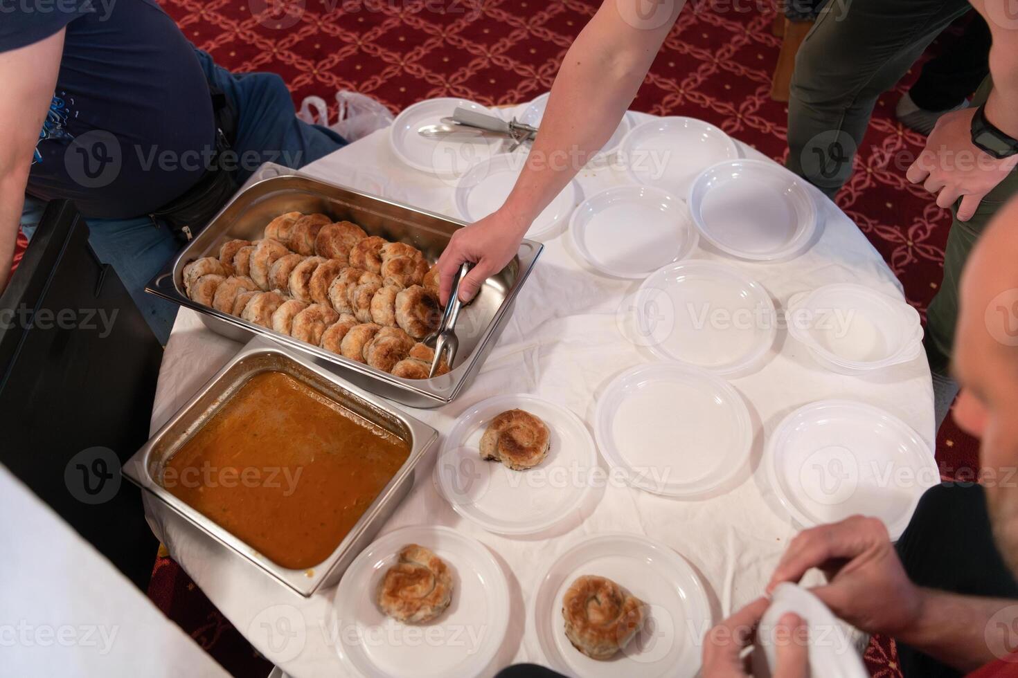 Top view of people serving food at a Mosque a communal meal during Ramadan before breaking the fast on Iftar dinner. Warm festive atmosphere celebrating Ramadan Karim and Eid, the Islamic holy month photo