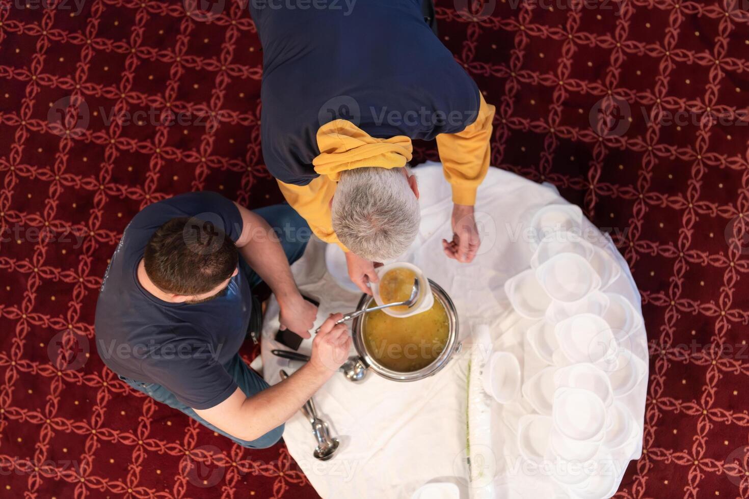 Top view of people serving food at a Mosque a communal meal during Ramadan before breaking the fast on Iftar dinner. Warm festive atmosphere celebrating Ramadan Karim and Eid, the Islamic holy month photo