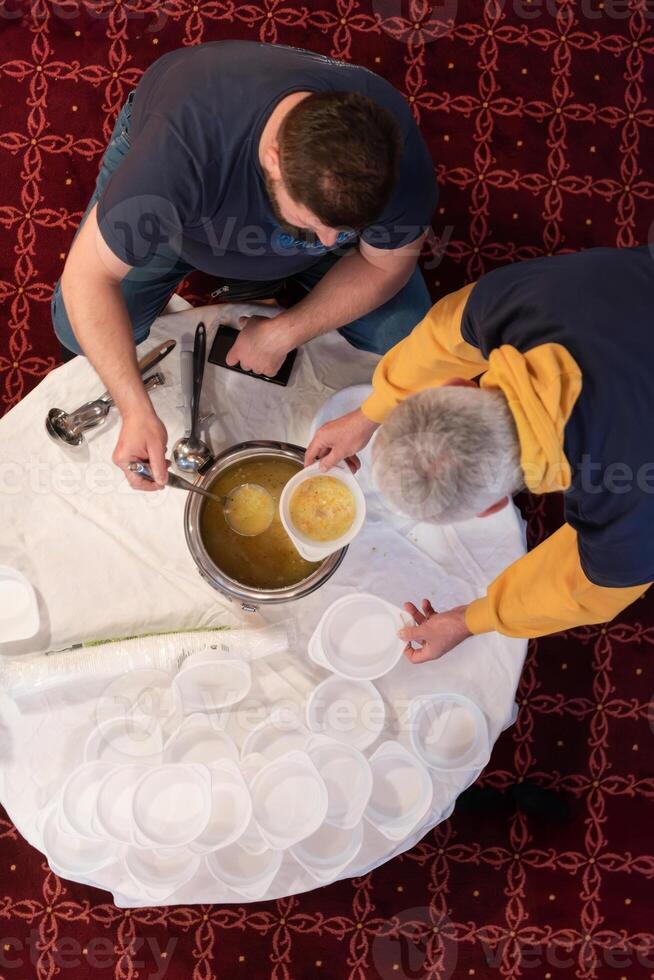 Top view of people serving food at a Mosque a communal meal during Ramadan before breaking the fast on Iftar dinner. Warm festive atmosphere celebrating Ramadan Karim and Eid, the Islamic holy month photo