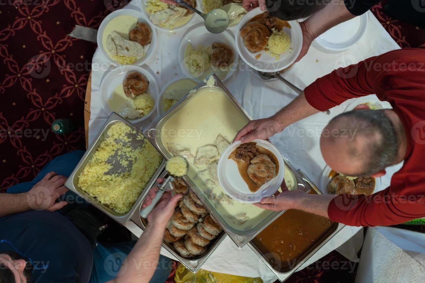 Top view of people serving food at a Mosque a communal meal during Ramadan before breaking the fast on Iftar dinner. Warm festive atmosphere celebrating Ramadan Karim and Eid, the Islamic holy month photo