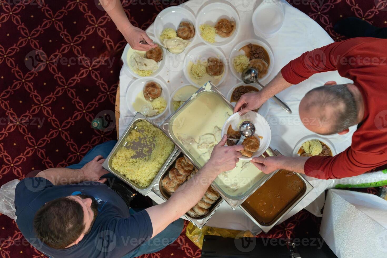 Top view of people serving food at a Mosque a communal meal during Ramadan before breaking the fast on Iftar dinner. Warm festive atmosphere celebrating Ramadan Karim and Eid, the Islamic holy month photo
