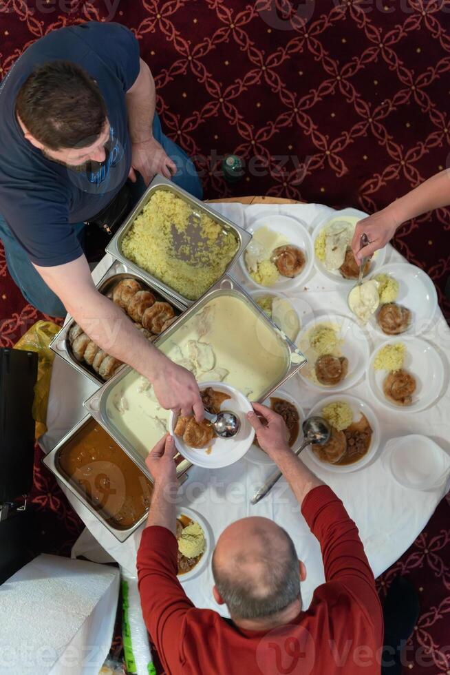 Top view of people serving food at a Mosque a communal meal during Ramadan before breaking the fast on Iftar dinner. Warm festive atmosphere celebrating Ramadan Karim and Eid, the Islamic holy month photo