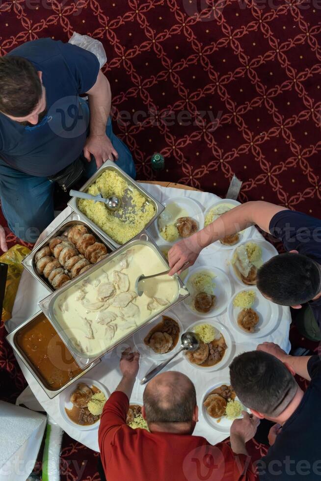 Top view of people serving food at a Mosque a communal meal during Ramadan before breaking the fast on Iftar dinner. Warm festive atmosphere celebrating Ramadan Karim and Eid, the Islamic holy month photo