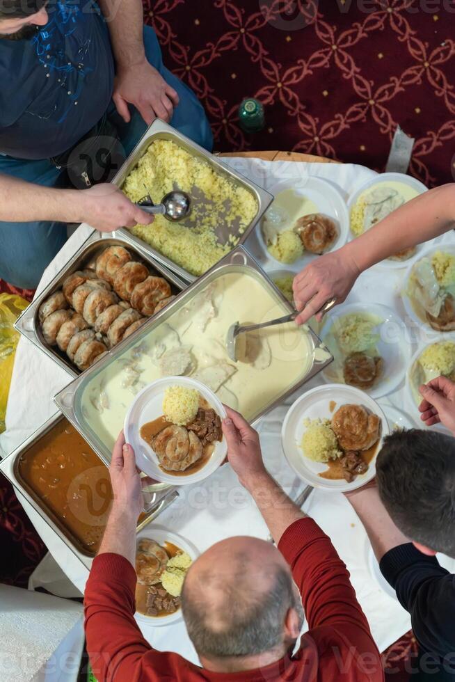 Top view of people serving food at a Mosque a communal meal during Ramadan before breaking the fast on Iftar dinner. Warm festive atmosphere celebrating Ramadan Karim and Eid, the Islamic holy month photo