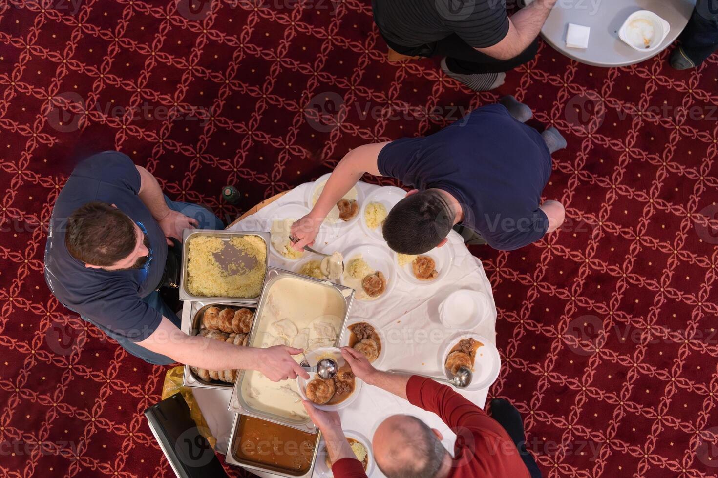 Top view of people serving food at a Mosque a communal meal during Ramadan before breaking the fast on Iftar dinner. Warm festive atmosphere celebrating Ramadan Karim and Eid, the Islamic holy month photo