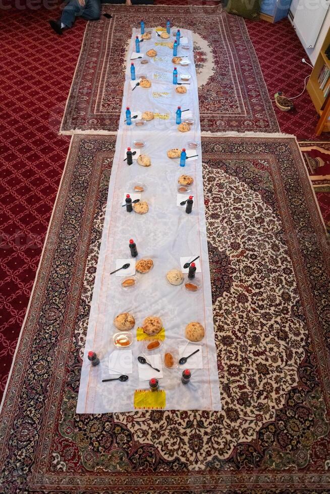 Top view of people serving food at a Mosque a communal meal during Ramadan before breaking the fast on Iftar dinner. Warm festive atmosphere celebrating Ramadan Karim and Eid, the Islamic holy month photo