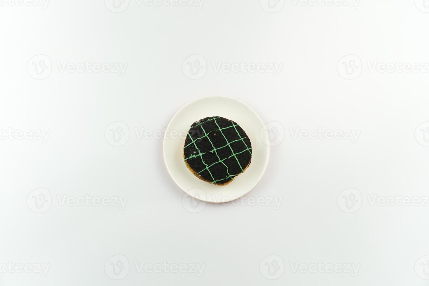 A cookie on a white plate with a black and green pattern photo