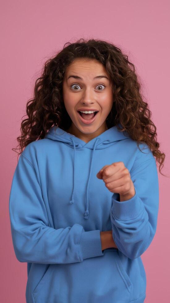 A young woman in a blue sweatshirt pointing at something photo