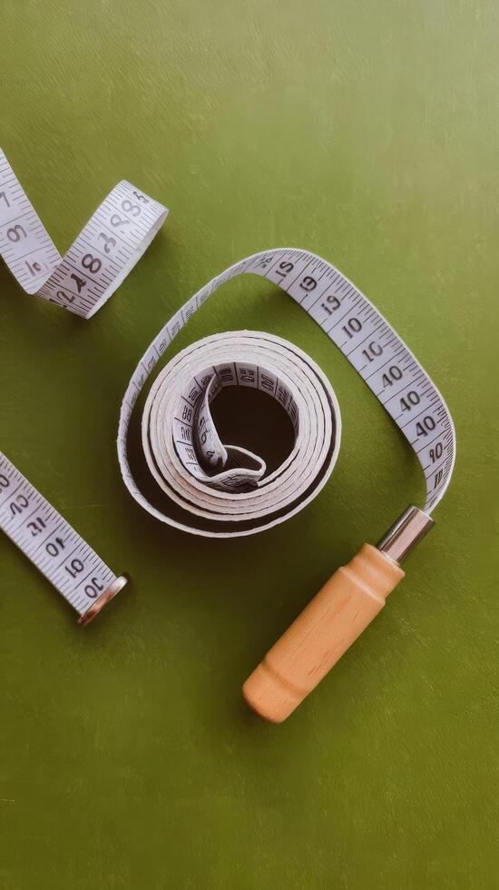 A measuring tape and a wooden ruler on a green surface photo