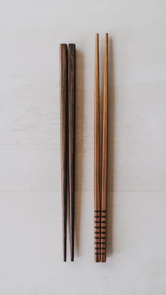 Two chopsticks with wooden handles on a white surface photo