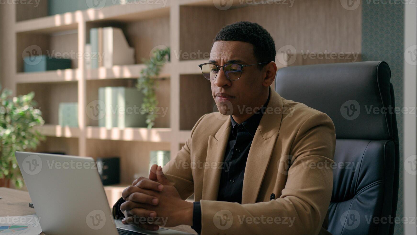 African American businessman ethnic puzzled man employer manager CEO entrepreneur working with laptop at office commerce work planning business startup solve issue think idea problem solution doubt photo