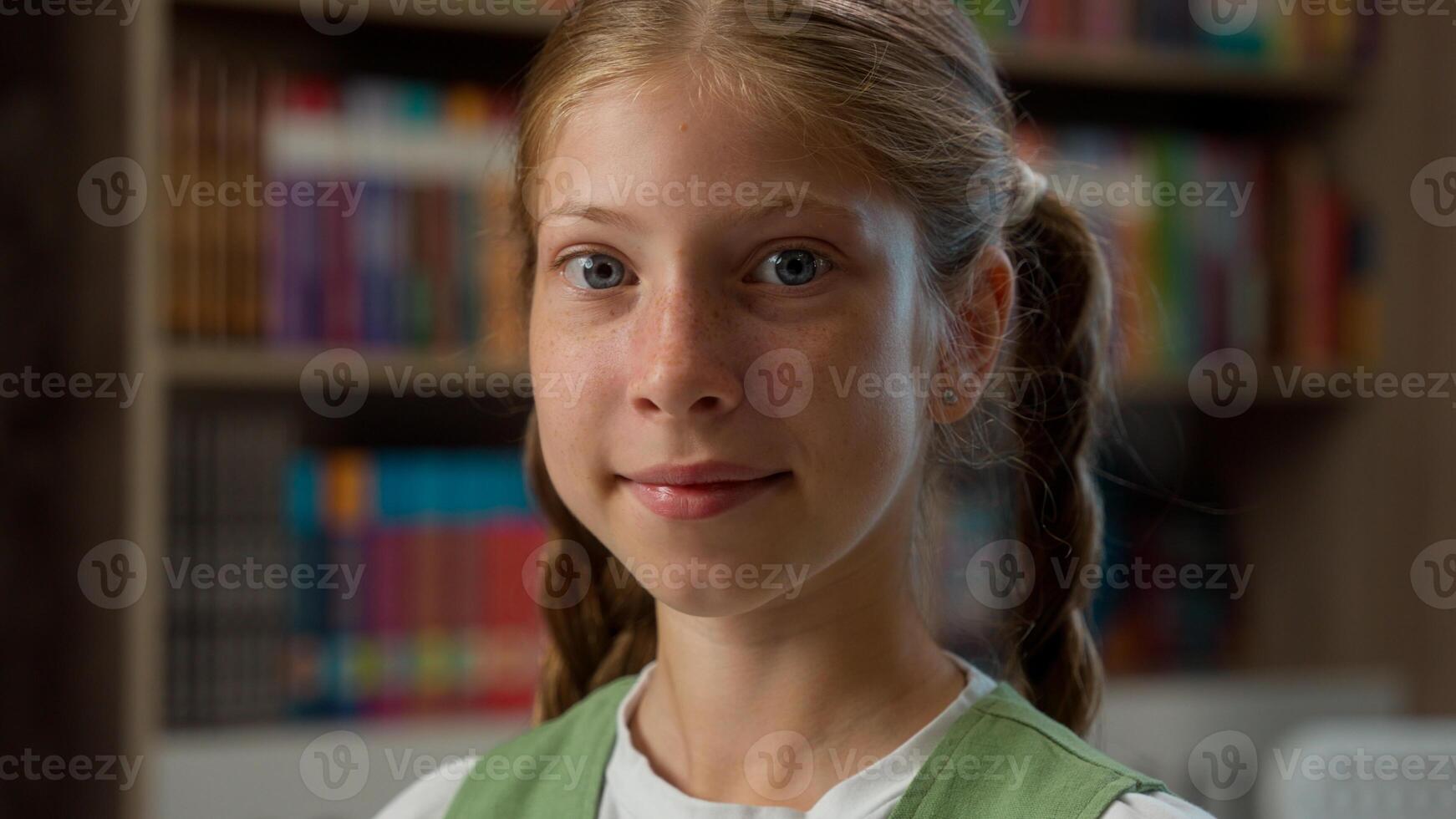 Close up happy jolly Caucasian little girl school child kid pupil schoolgirl excited student primary school education joyful learner clapping hands applauding smiling looking at camera inside library photo