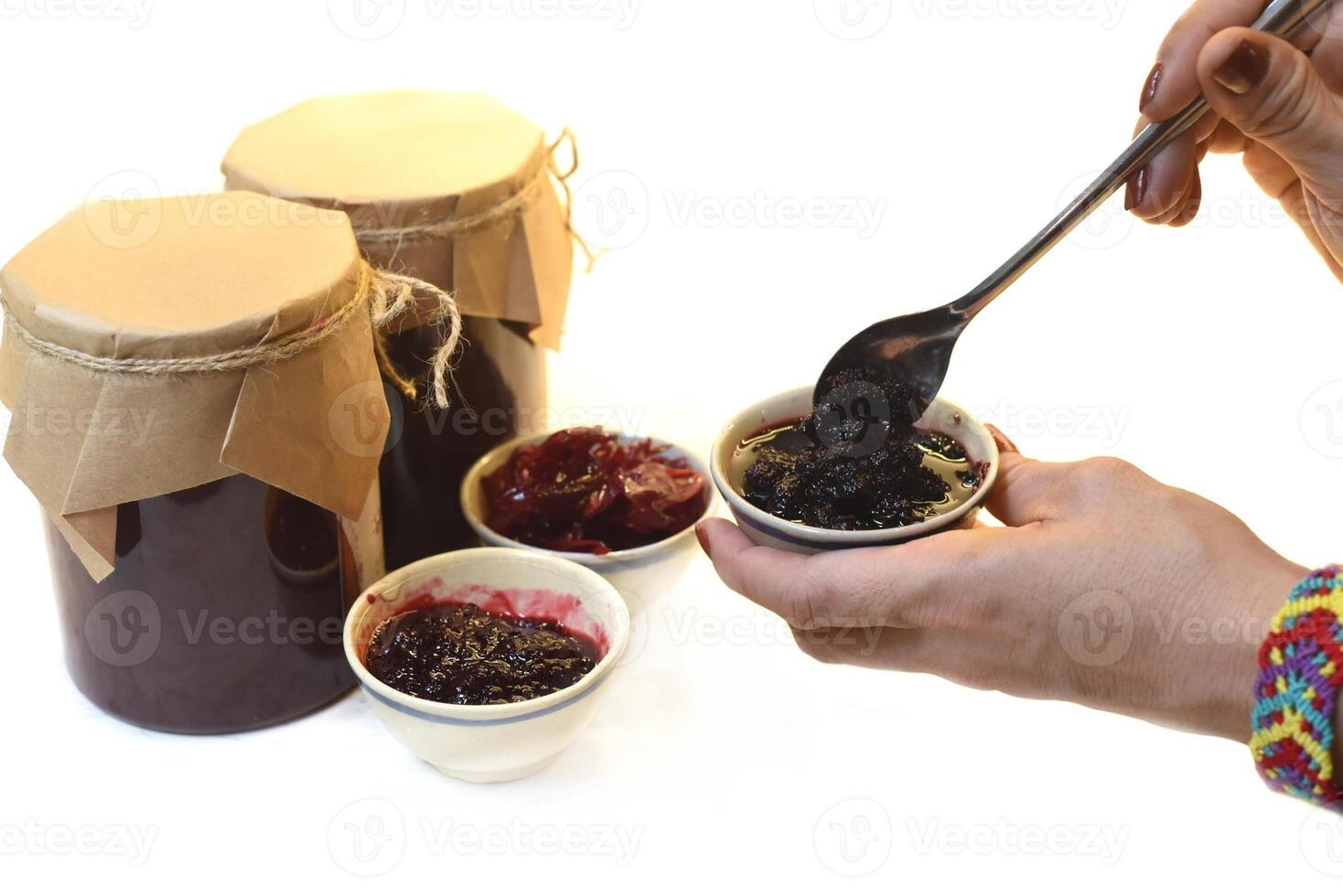 Hand serving homemade mulberry jam in small bowls from jars photo