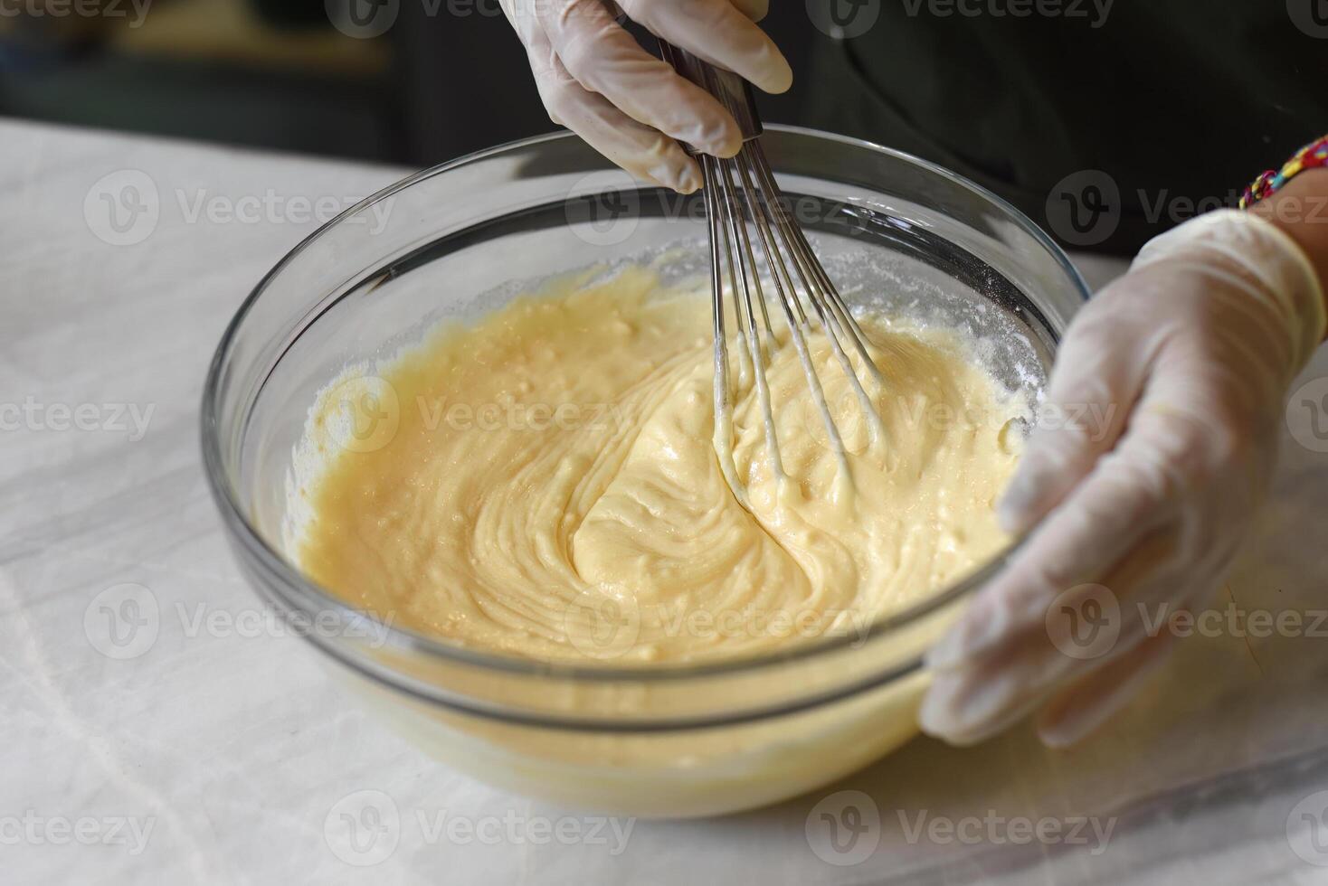 A hands in rubber gloves stirring eggs for dough photo