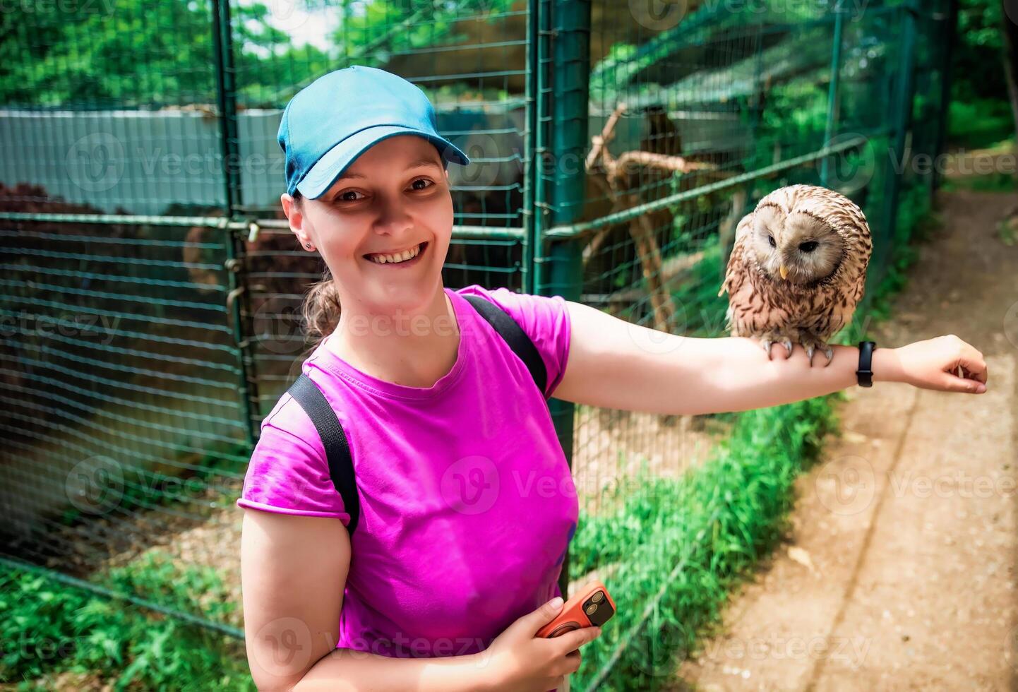 Portrait of laughing 36 years old Russian woman with Ural owl Strix uralensis bird sitting on her arm photo