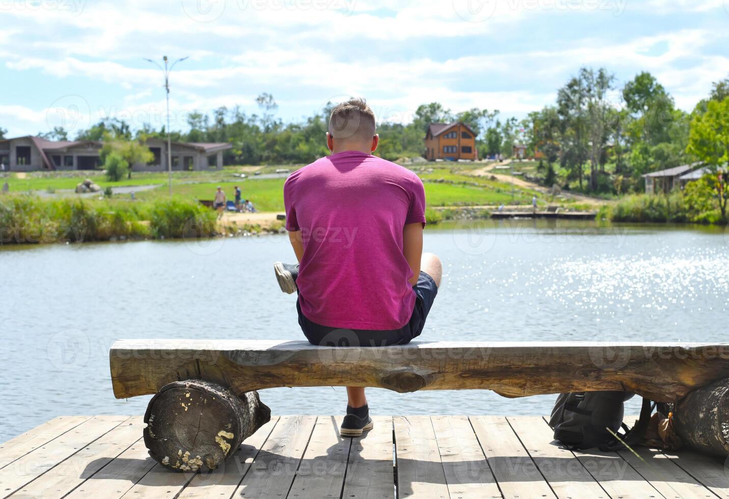 Young man sitting on a bench against lake photo