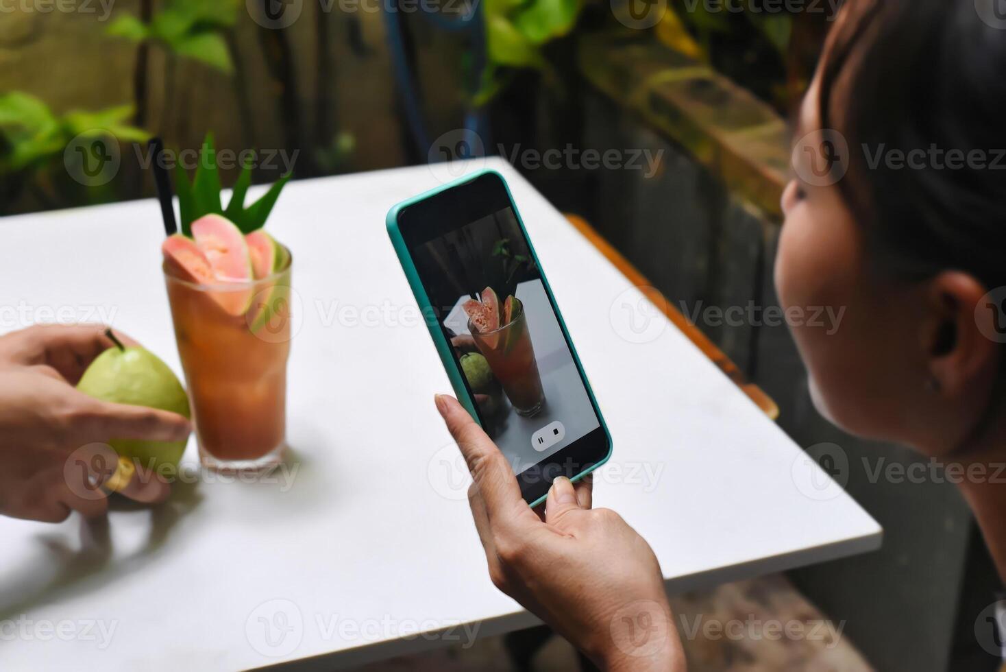 A woman taking picture of guava tea for advertisement and social media photo