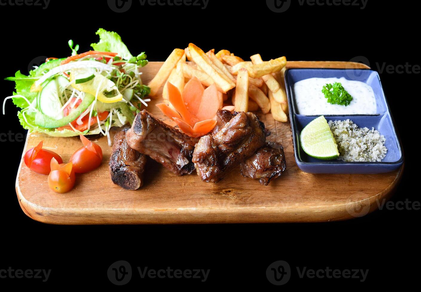 Grilled smoked pork ribs with french fries and sauces on wooden board on a black background side view photo
