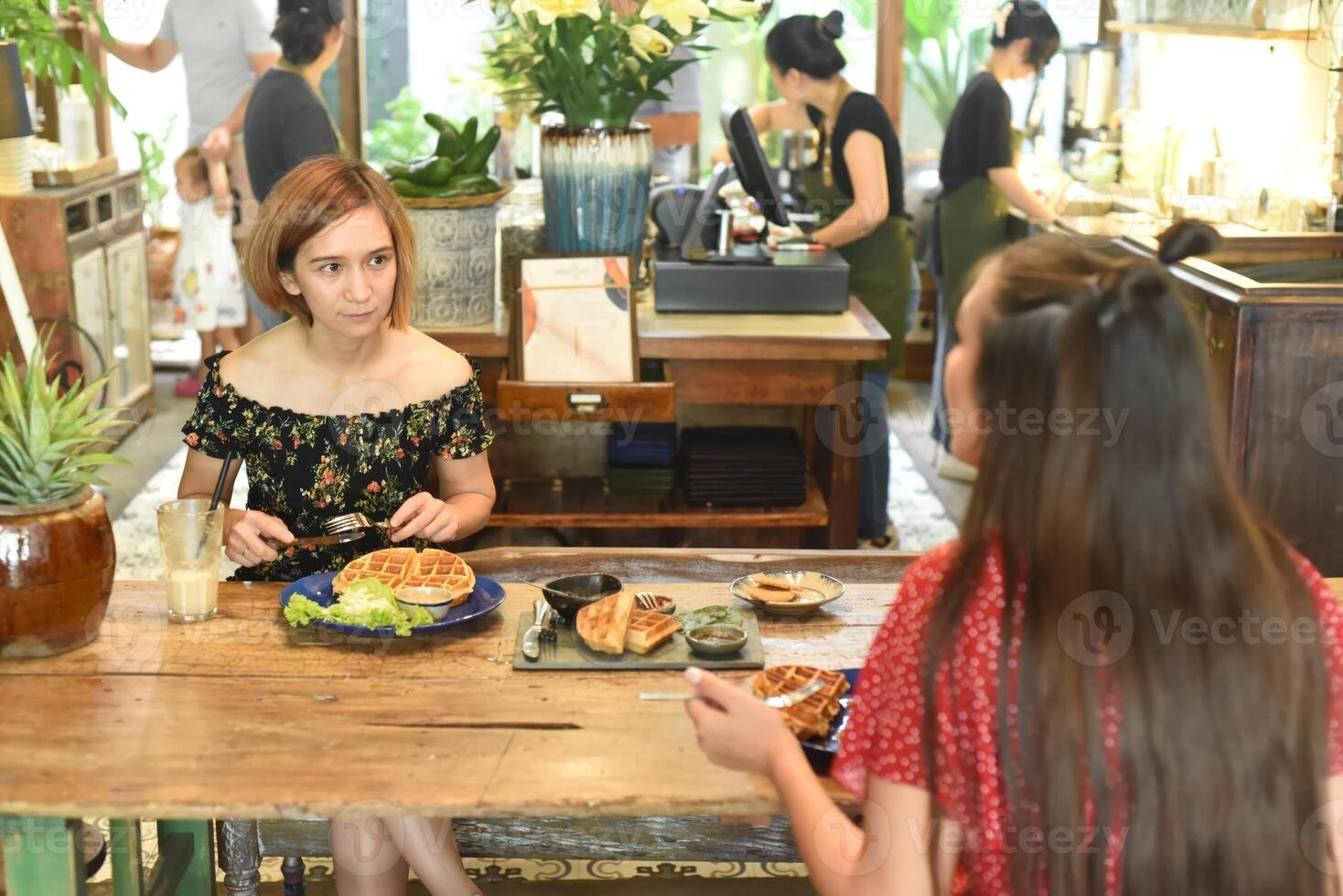 Young women chatting and eating waffles in photo