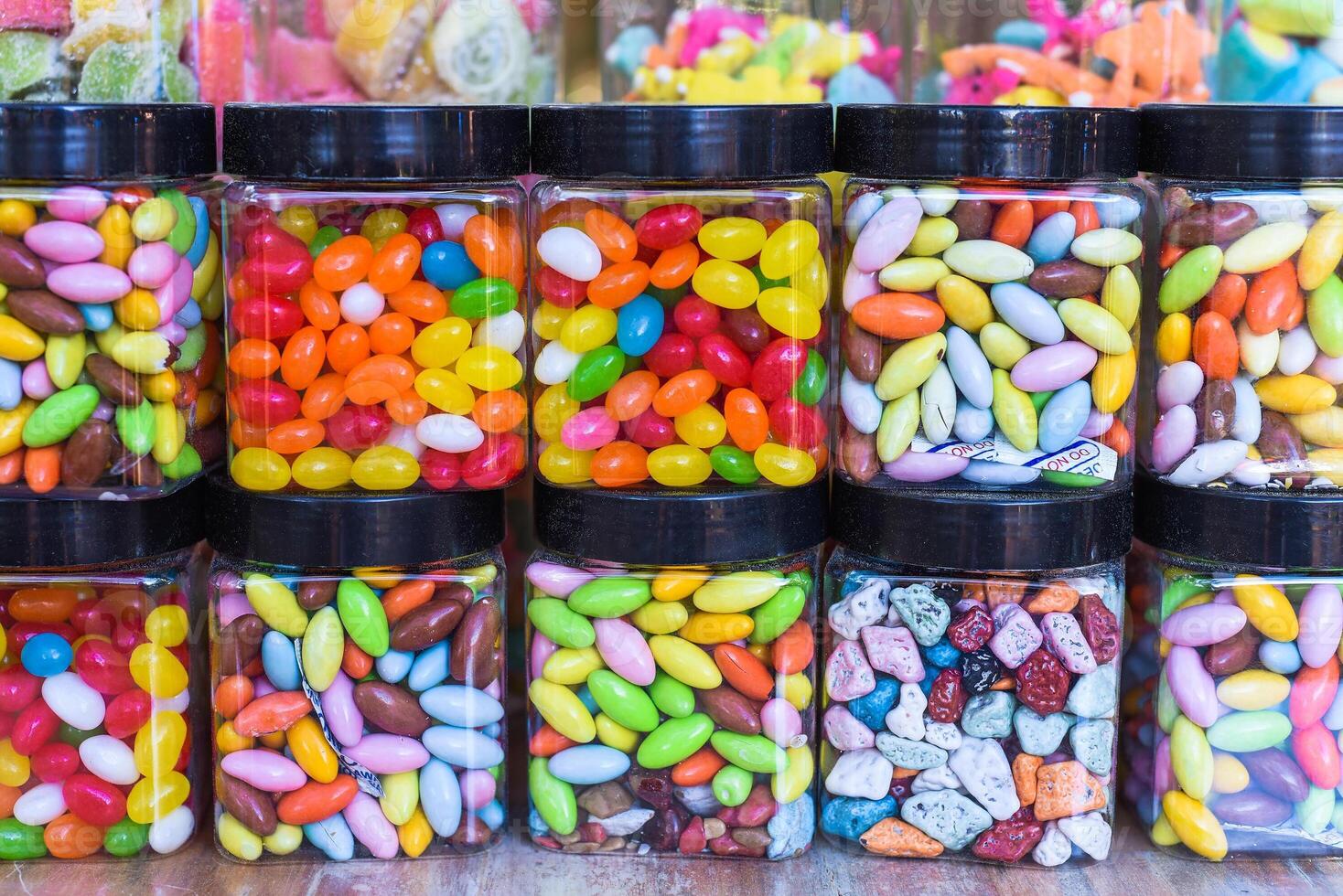 Many colorful candy and lollipops with gum in jar photo