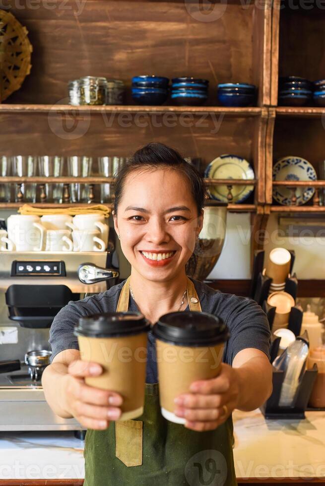 Vietnamese smiling waitress holds paper cups with coffee in a cafe photo