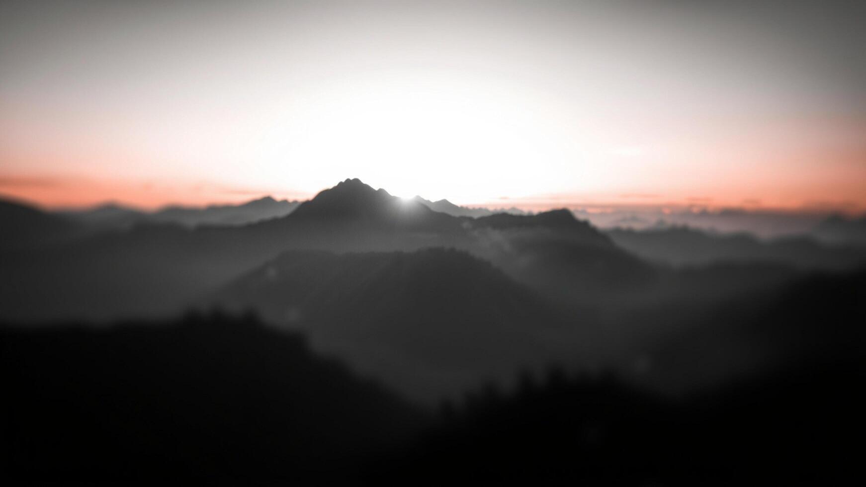 A blurry image of a mountain range with the sun rising photo