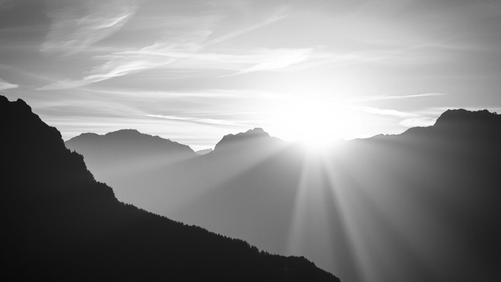 Black and white photo of mountain range with sun shining through