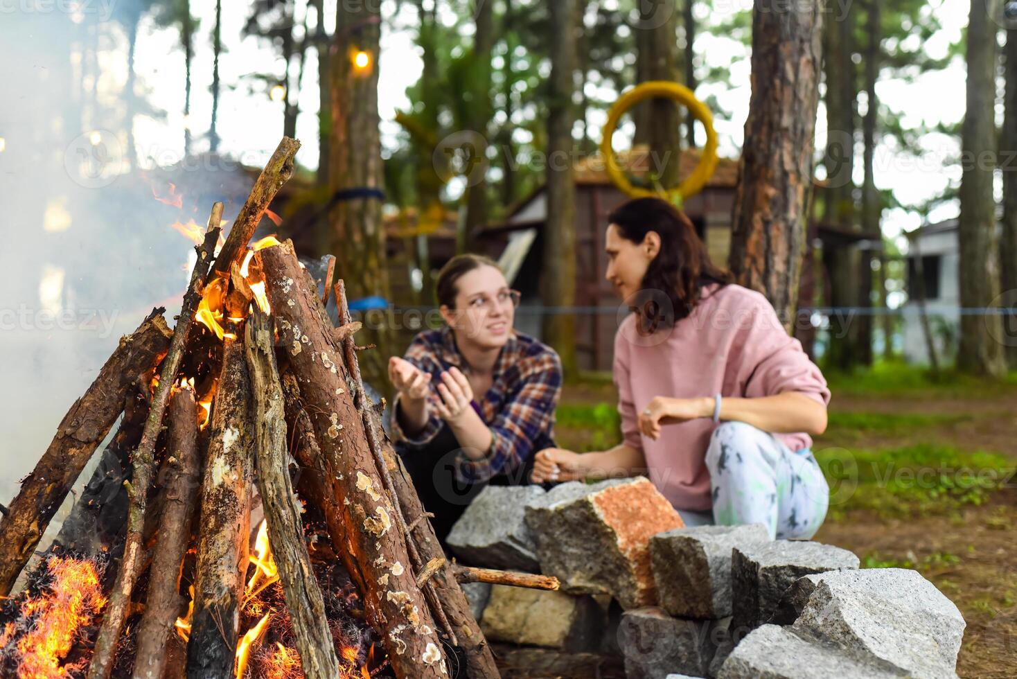 Mother with her daughters spend time together, kindle a fire and throw sticks photo