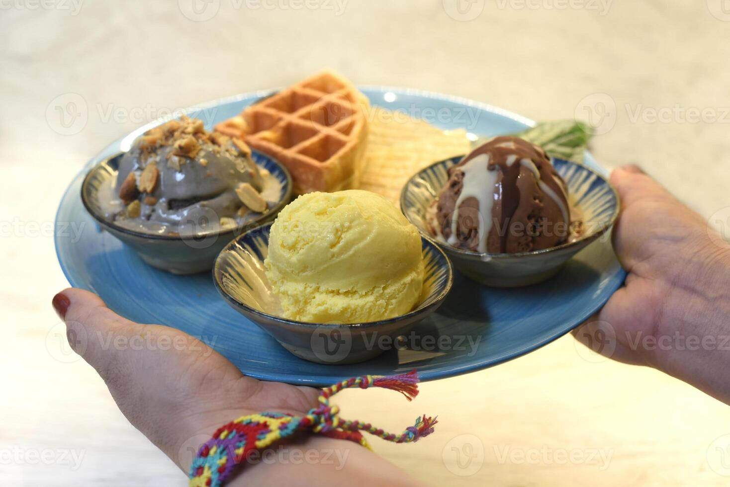 Woman's hand holding homemade ice cream with waffle on plate with chocolate syrup photo