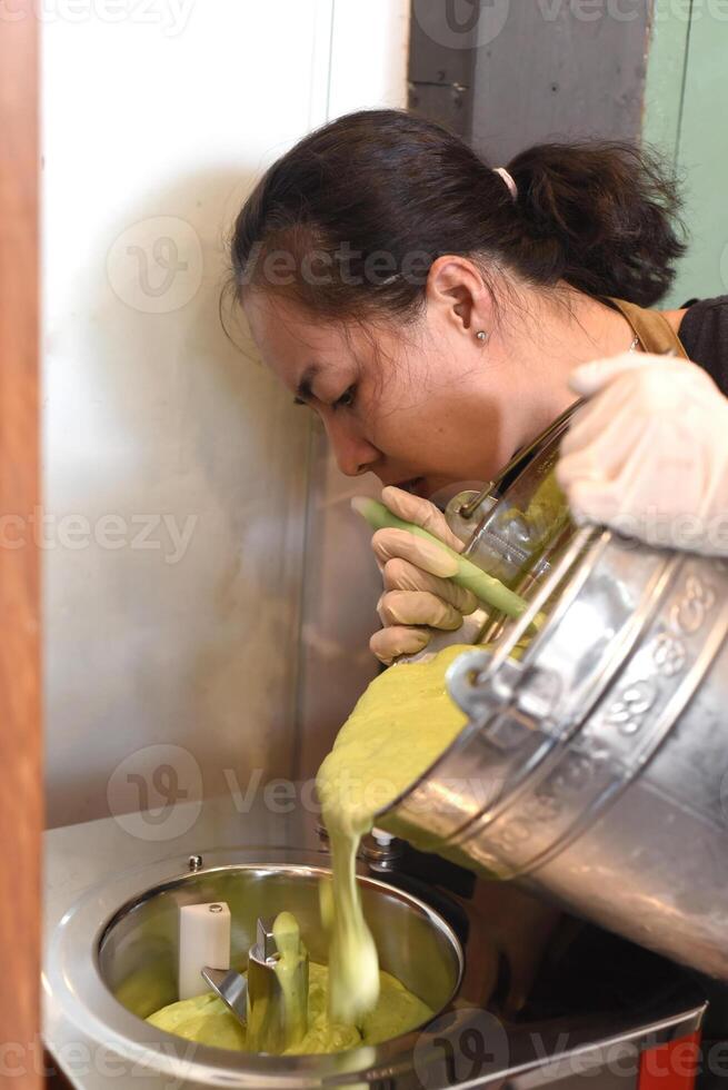 Vietnamese woman shifting homemade ice cream from bucket into mixer photo