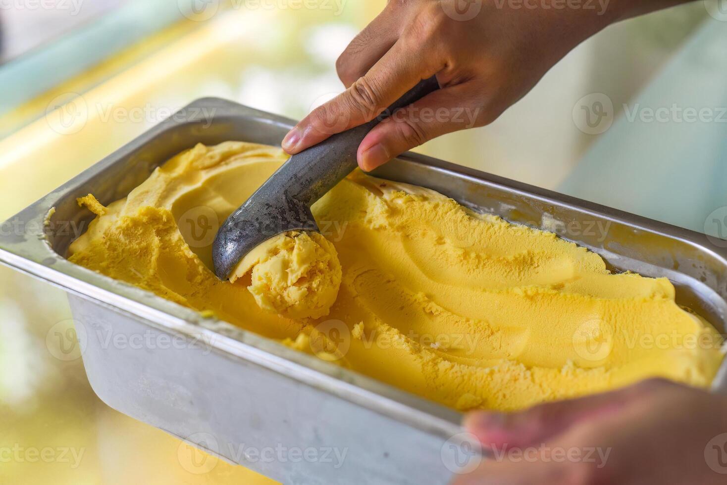 hand scooping a scoop of Passion fruit ice cream into a spoon in fridge photo